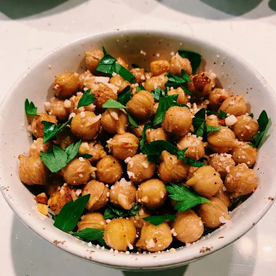 - 1 can (15 oz) chickpeas - 2 tablespoons olive oil - 4 cloves garlic Chickpeas are the star of this recipe. They give us a great base. Make sure to rinse and drain them well. Olive oil adds healthy fat and helps the chickpeas crisp up. Garlic brings flavor and aroma, making everything more delicious. - 1/2 teaspoon smoked paprika - 1/2 teaspoon salt - 1/4 teaspoon black pepper Smoked paprika gives a nice, warm flavor. Salt enhances the taste of the chickpeas. Black pepper adds a little kick. Together, they create a great seasoning mix. - 1/4 cup grated Parmesan cheese - 1 tablespoon fresh parsley, chopped Parmesan cheese melts slightly and adds richness. Fresh parsley adds color and a fresh taste. Sprinkle the cheese on hot chickpeas for the best flavor. It will stick well and create a lovely topping. {{ingredient_image_1}} 1. Preheat your oven to 400°F (200°C). Line a baking sheet with parchment paper. This helps the chickpeas roast evenly. 2. Open the can of chickpeas. Rinse them under cold water. Drain well. Pat them dry with a clean kitchen towel. This step removes extra moisture. 1. In a large bowl, add the rinsed and drained chickpeas. 2. Drizzle two tablespoons of olive oil over the chickpeas. 3. Add four minced garlic cloves, half a teaspoon of smoked paprika, half a teaspoon of salt, and a quarter teaspoon of black pepper. 4. Toss the chickpeas well to coat them evenly with oil and seasonings. 1. Spread the chickpeas in a single layer on your prepared baking sheet. 2. Roast them in the preheated oven for 25 to 30 minutes. Shake the pan halfway through cooking. This helps them get crispy on all sides. 3. Check for a golden color and a crunchy texture. 4. Once done, remove the chickpeas from the oven. Immediately sprinkle a quarter cup of grated Parmesan cheese over them. Toss gently to mix the cheese. 5. Let them cool for a few minutes. Transfer to a bowl and garnish with one tablespoon of fresh chopped parsley. Enjoy your crunchy snack! To get that perfect crunch, you must dry the chickpeas well. After rinsing and draining, use a clean towel to pat them dry. This step helps them roast evenly. Different ovens may cook at different rates. If your oven runs hot, check the chickpeas early. If they are not golden yet, let them roast a little longer. You can make these chickpeas even tastier by adding more flavors. Try herbs like oregano or thyme for a fresh twist. For a spicy kick, add cayenne pepper or chili powder. If you want a cheese-free version, nutritional yeast gives a cheesy flavor without dairy. You can also switch up the oils. Avocado oil or melted coconut oil can change the taste too. These roasted chickpeas are great on their own, but they shine when paired with dips. Try them with hummus or tzatziki for a tasty snack. You can also use them as a topping on salads. They add a nice crunch and extra protein to your meal. Enjoy them anytime you want a quick, healthy snack! Pro Tips Dry Chickpeas Thoroughly: Ensuring the chickpeas are completely dry before roasting will help them achieve maximum crispiness. Customize Seasoning: Feel free to experiment with different spices such as cayenne pepper or Italian herbs for unique flavor variations. Use Fresh Garlic: Freshly minced garlic provides a stronger flavor than pre-minced or powdered garlic, enhancing the dish's overall taste. Store in an Airtight Container: To maintain their crunchiness, store any leftover roasted chickpeas in an airtight container at room temperature for up to a week. {{image_2}} You can easily change the taste of Garlic Parmesan Roasted Chickpeas. One option is Spicy Garlic Parmesan Roasted Chickpeas. To make this, just add some cayenne pepper or chili powder to the mix. Start with a pinch and adjust to your taste. The heat pairs well with the garlic and cheese, making each bite a bit thrilling. Another fun option is Herb-infused Roasted Chickpeas. You can add dried herbs like oregano, thyme, or rosemary. These herbs bring a unique flavor and aroma. Simply mix them in with your other seasonings before roasting. If you're looking for vegan substitutes for Parmesan cheese, you have choices. Nutritional yeast is a great option. It has a cheesy flavor and is packed with nutrients. Use the same amount as Parmesan for a similar taste. For those needing gluten-free alternatives, rejoice! This recipe is already gluten-free since chickpeas do not contain gluten. Just ensure that any added spices or toppings are also gluten-free. When it comes to appetizer vs. snack options, these roasted chickpeas fit both roles perfectly. Serve them as a fun, crunchy appetizer at a party. Guests will love the flavor and texture. Or, keep them handy as a quick snack during your day. They are healthy and satisfying, making them a great choice any time. To store your leftover garlic Parmesan roasted chickpeas, let them cool completely. Use an airtight container to keep them fresh. You can place them in a glass or plastic container. Avoid using a bag, as it can trap moisture. This keeps the chickpeas crispy for a few days. Roasted chickpeas can be frozen for longer storage. Place them in a freezer-safe bag or container. Make sure to remove as much air as possible. To reheat, preheat your oven to 350°F (175°C). Spread the frozen chickpeas on a baking sheet. Bake for about 10-15 minutes until they are warm and crispy again. This method helps maintain their crunch. Garlic Parmesan roasted chickpeas stay fresh for about 3-4 days in the fridge. If you freeze them, they can last up to 3 months. Always check for any changes in smell or texture before eating. Enjoy your crunchy snack at any time! You can use nutritional yeast for a dairy-free option. It adds a cheesy flavor without dairy. Another option is using vegan Parmesan, made from nuts and spices. If you prefer, you can try pecorino cheese for a similar taste. Yes, you can use dried chickpeas. Soak them overnight in water. This softens them. After soaking, drain and rinse them. Boil them for about 1-2 hours until soft. Let them cool before roasting. Add cayenne pepper for heat. Start with just a pinch, then taste. You can also mix in some chili powder for more flavor. For a different kick, use crushed red pepper flakes. Adjust the amount to your spice level. This blog post covered a simple and tasty roasted chickpeas recipe. You learned about the main ingredients and steps involved, from preparation to roasting. We discussed tips for perfect crispiness and how to enhance flavors. Variations and storage tips helped you see more options. Roasted chickpeas make a great snack or appetizer. Enjoy experimenting with flavors and serving ideas. Armed with this knowledge, you can now make your own crunchy delights.